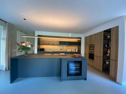 Moderne keuken met een kookeiland, houten kasten en een grote vensterpartij.